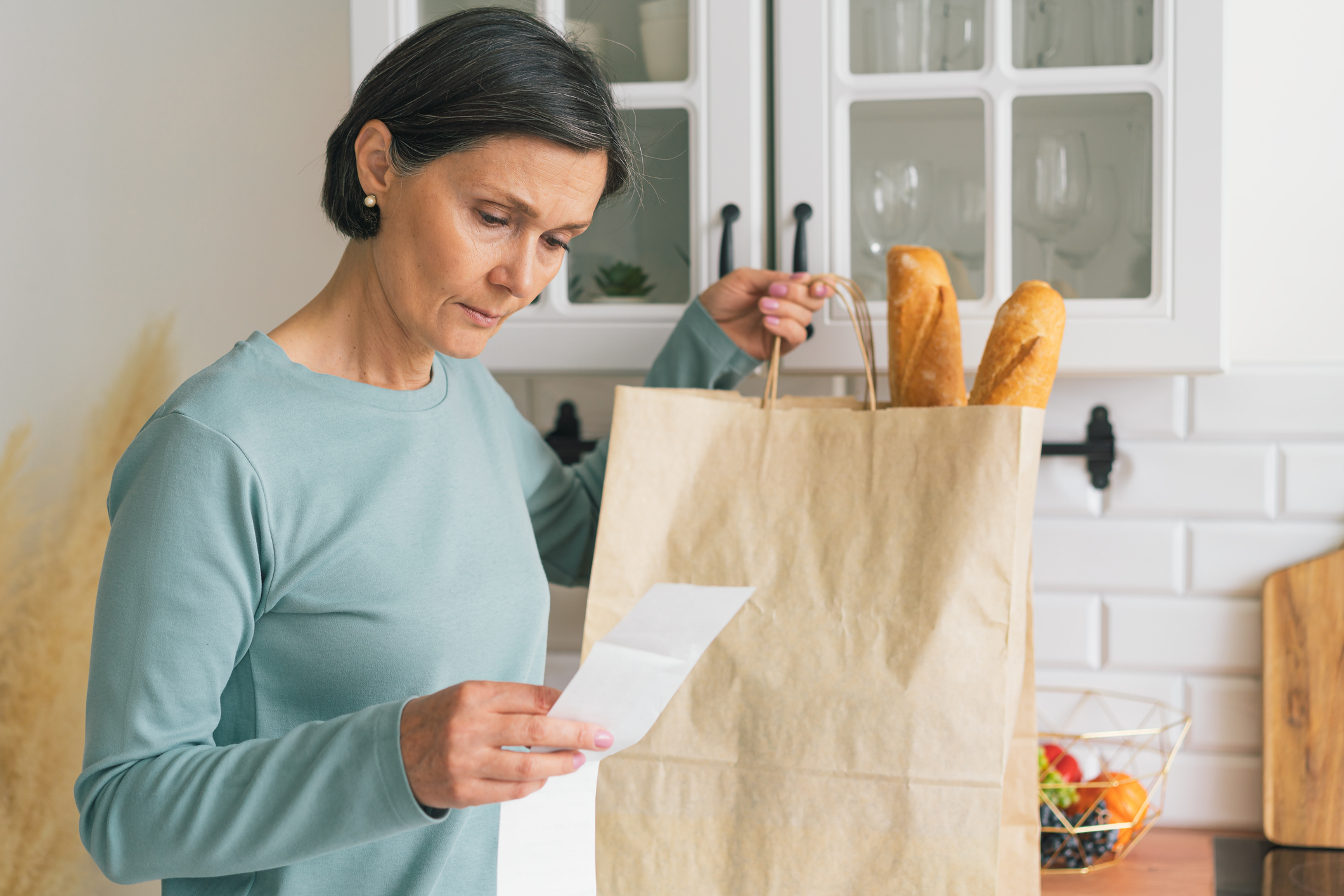 A woman carefully reviewing a long grocery receipt with a focused and satisfied expression.