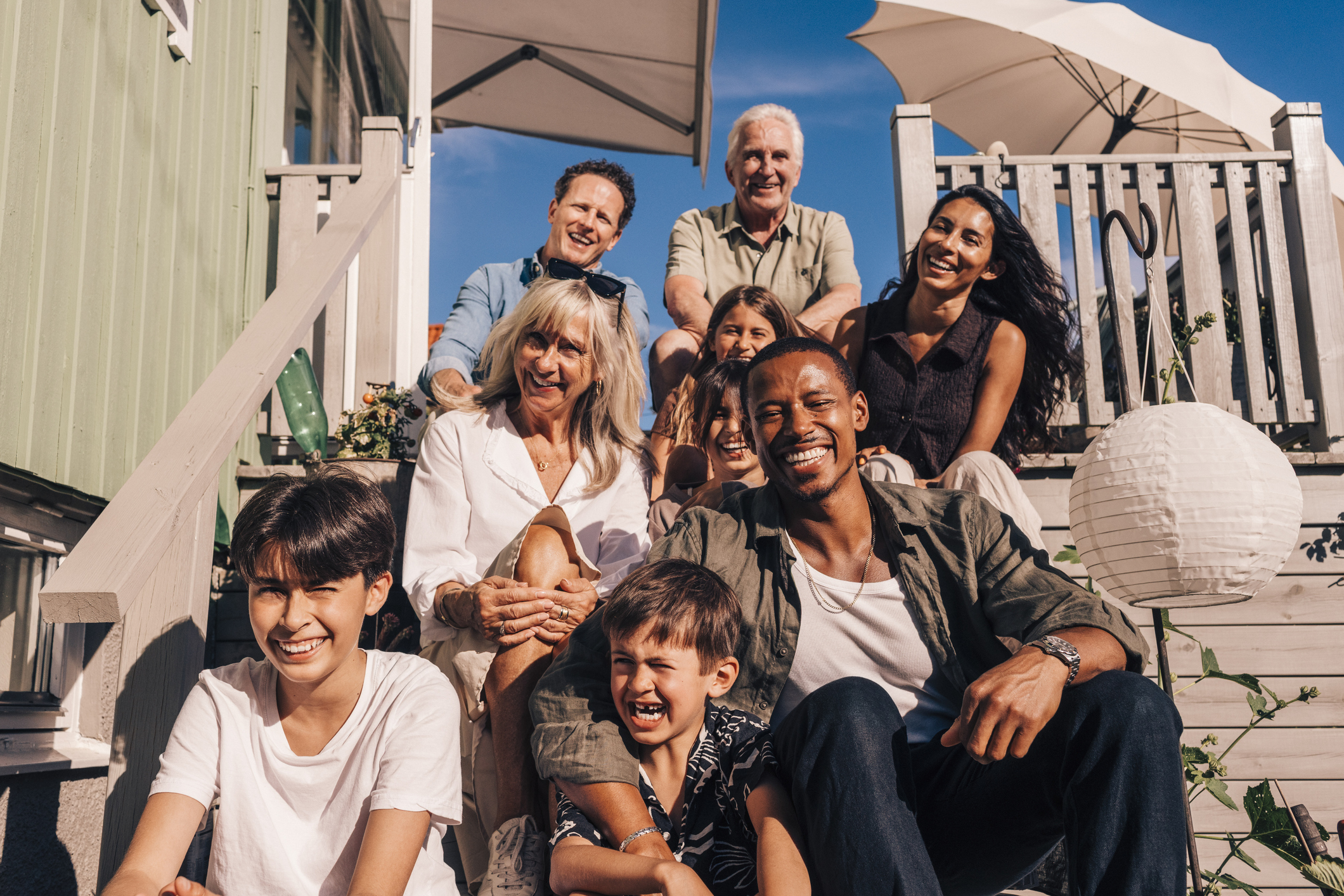 A happy family sitting on the steps of a beautiful house by the beach.