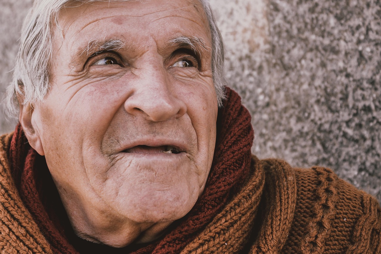 A smiling senior man outdoors showing healthy teeth after restorative work.